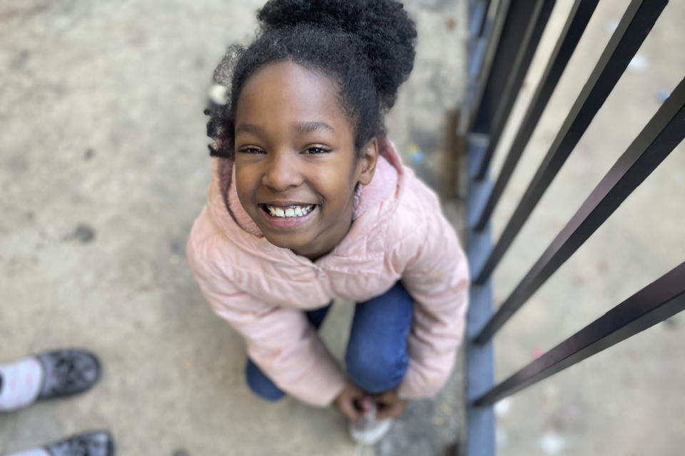 Tameka's 8-year-old daughter ties her shoe before running out to play in Atlanta on Dec. 5, 2023. The little girl should be in second grade but has never attended school. Tameka's kids have essentially been out of school since COVID hit in March 2020. They have had a consistent place to live, but nearly everything else in their lives collapsed during the pandemic. (AP Photo/Bianca Vázquez Toness)