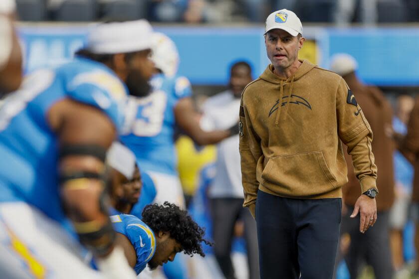 Chargers coach Brandon Staley walks among players as they warm up before playing the Detroit Lions