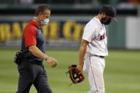 Boston Red Sox infielder Jose Peraza, right, leaves the field with a trainer after being injured while pitching during the ninth inning of a baseball game against the Tampa Bay Rays, Thursday, Aug. 13, 2020, in Boston. (AP Photo/Michael Dwyer)