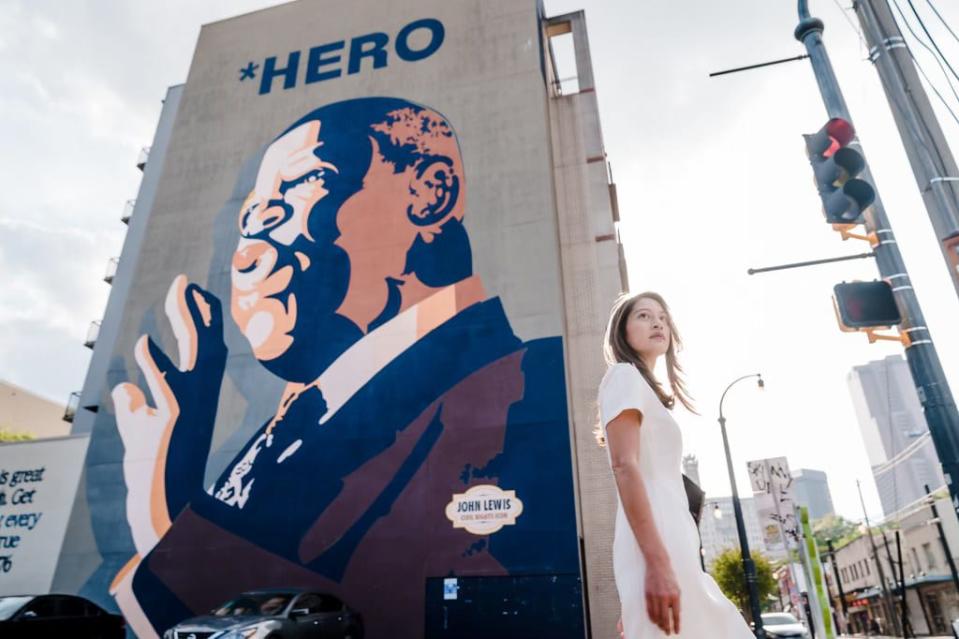 Image: Bee Nguyen poses in front of a mural of John Lewis. (Kevin Lowery)