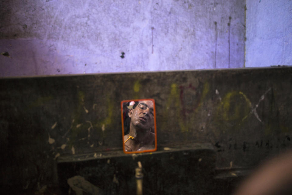 In this March 19, 2020 photo, Cesar Alegre is reflected in a mirror as he prepares for his day in the communal bathroom of a deteriorating building nicknamed “Luriganchito” after the country’s most populous prison, in Lima, Peru. Sometimes Alegre begs in markets; sometimes he sells candies. It is a task that was hard at the best of times, but with a month-long quarantine that has forced millions of Peruvians to stay home to help curb the spread of the new coronavirus, it has become much harder. (AP Photo/Rodrigo Abd)