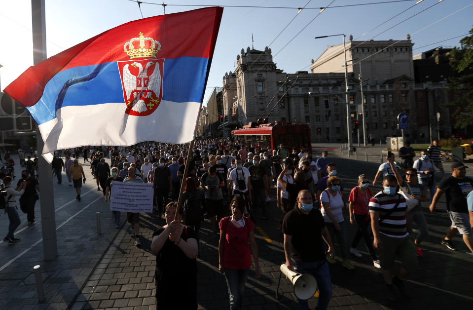 A women waves with Serbian nation flag as people gather for a demonstration in Belgrade, Serbia, Wednesday, July 8, 2020. Serbia's president Aleksandar Vucic backtracked Wednesday on his plans to reinstate a coronavirus lockdown in Belgrade after thousands protested the move and violently clashed with the police in the capital. (AP Photo/Darko Vojinovic)