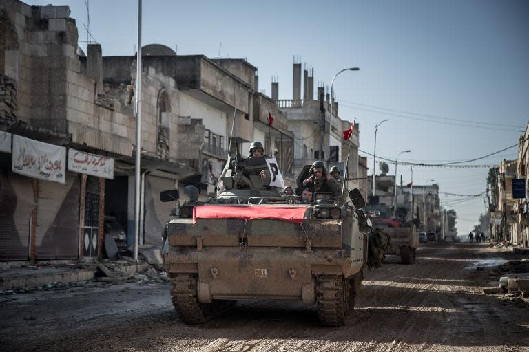 Turkish army vehicles drive in a street of the Syrian town of Kobane on February 22, 2015, during an operation to relieve the garrison guarding the Suleyman Shah mausoleum