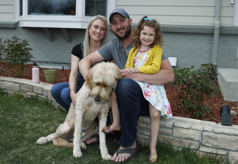 Eli Oderberg, center, sits with Katie Evers, left, their 4-year-old daughter, Everlee, and the couple's goldendoodle outside their home in southeast Denver on Thursday, April 30, 2020. Oderberg, like 30 million people around the United States who have filed for unemployment benefits after losing their jobs during the coronavirus pandemic, is facing the specter of paying the monthly rent with the flip of the calendar. (AP Photo/David Zalubowski)