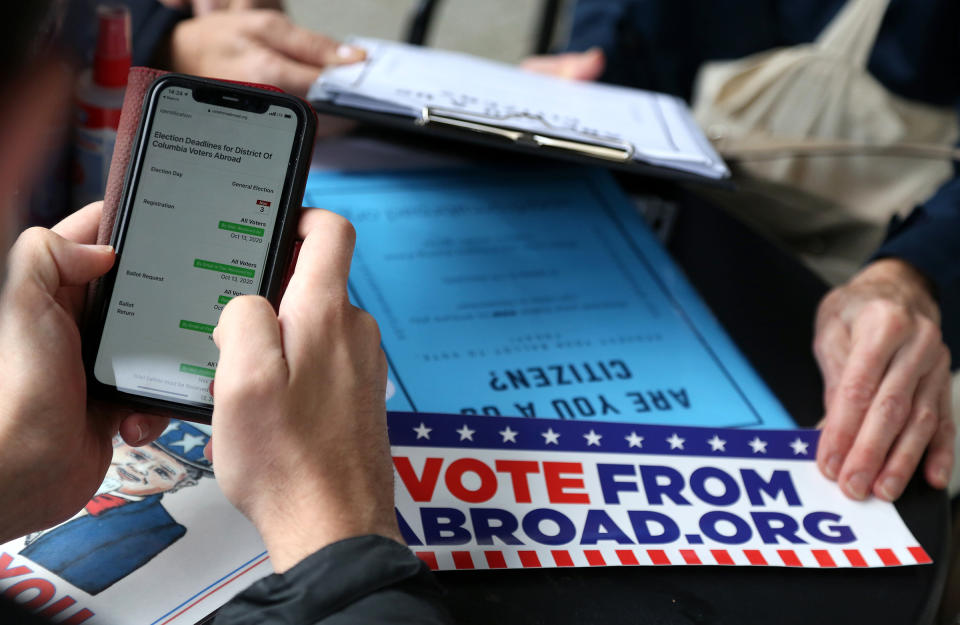 Florian Schiedhelm of Vote from Abroad (L) assists a U.S. citizen to register to vote absentee in the U.S. presidential elections to be held on November 3, at a Starbucks coffeeshop on Oct. 10, 2020 in Berlin, Germany.<span class="copyright">Adam Berry—Getty Images</span>