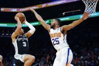 San Antonio Spurs forward Keldon Johnson (3) drives past Phoenix Suns forward Mikal Bridges (25) during the first half of an NBA basketball game Monday, Dec. 6, 2021, in Phoenix. (AP Photo/Ross D. Franklin)