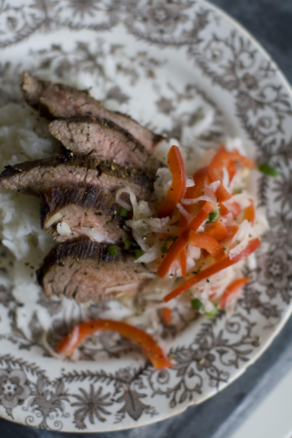 This Dec. 2, 2013 photo shows pan seared flank steak with daikon slaw in Concord, N.H. Daikon radish resemble giant white carrots, but have a mild peppery bite. (AP Photo/Matthew Mead)