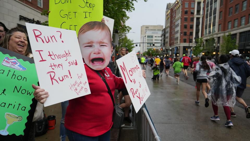 Susan Strohacker shows her baby-faced support for her daughter, Haley Strohacker, along the starting area of the 2022 Capital City Half Marathon on Saturday. Laughing with her is her friend Sherri Schumm.