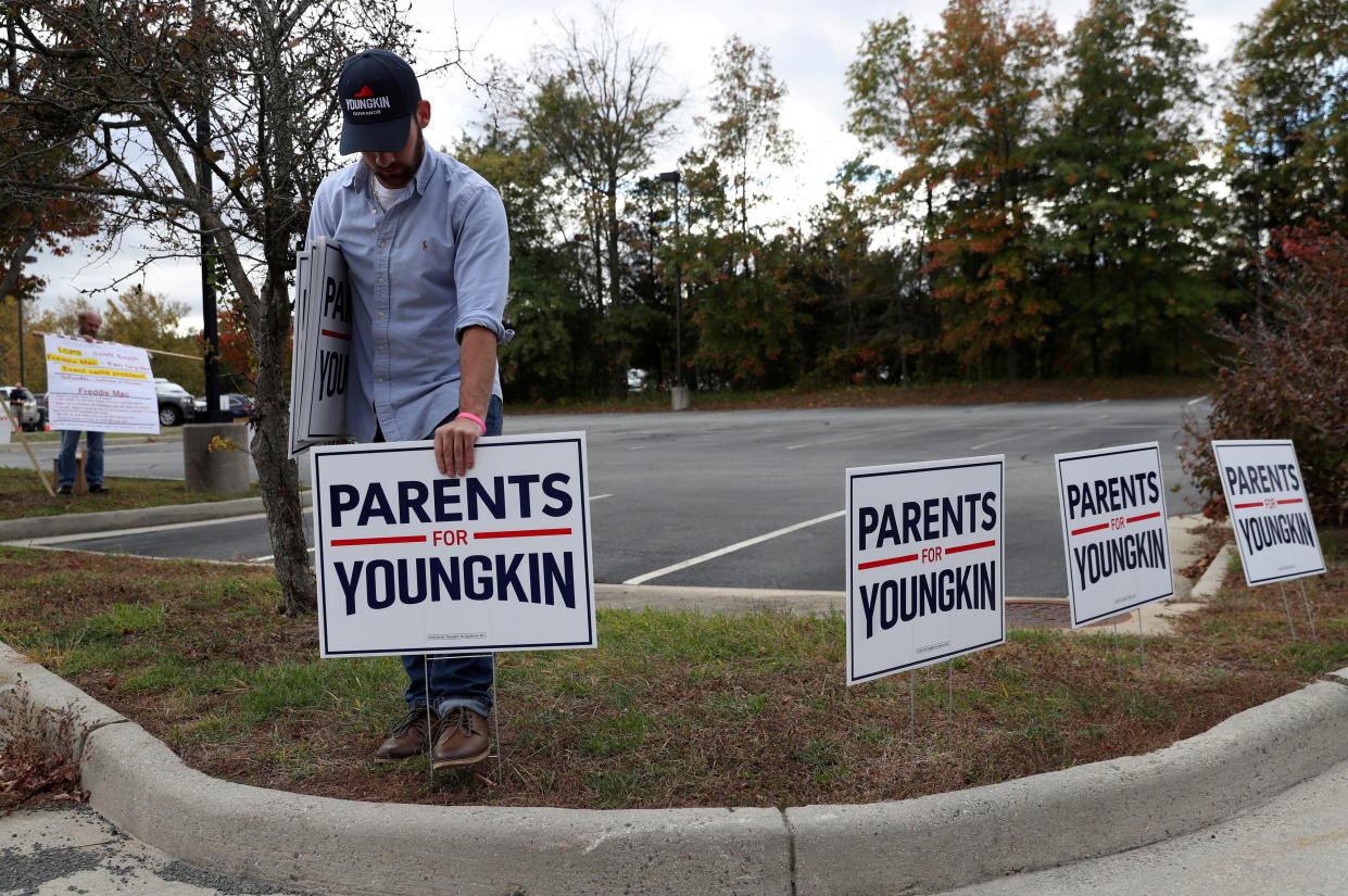 A Glenn Youngkin supporter puts signs up.