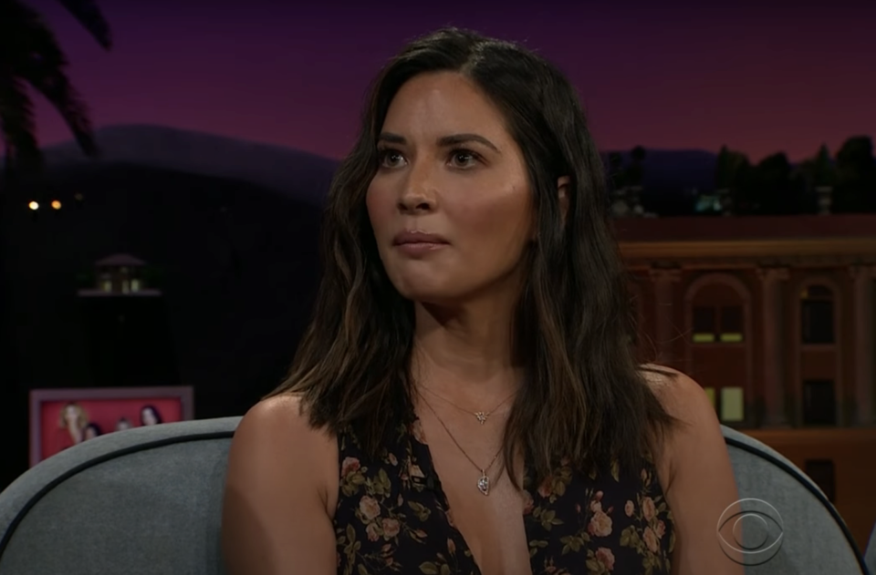 Olivia Munn in a floral dress during an interview on a talk show set