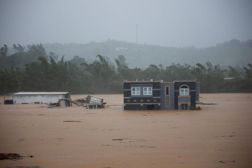 FOTO DE LA MEJOR CALIDAD DISPONIBLE - Tres personas dentro de una casa aguardan a ser rescatadas de las inundaciones provocadas por el huracán Fiona, el domingo 18 de septiembre de 2022, en Cayey, Puerto Rico. (AP Foto/Stephanie Rojas)