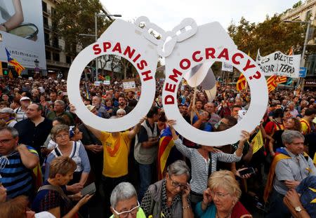 People hold a giant pair of handcuffs during a demonstration organised by Catalan pro-independence movements ANC (Catalan National Assembly) and Omnium Cutural, following the imprisonment of their two leaders Jordi Sanchez and Jordi Cuixart, in Barcelona, Spain October 21, 2017. REUTERS/Rafael Marchante