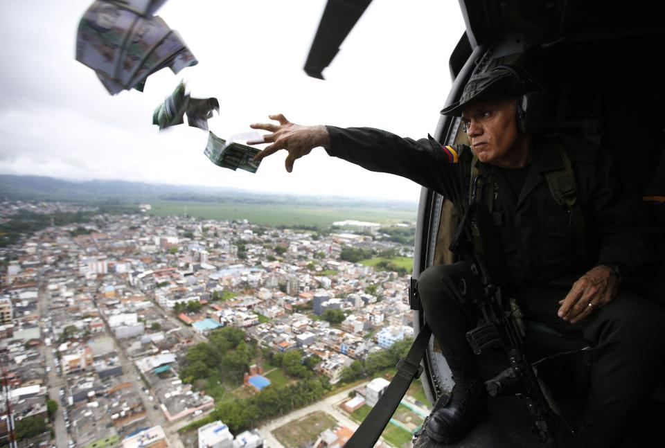 En esta imagen, tomada el 31 de mayo de 2017, el comandante de la unidad antinarcóticos de la policía, José Mendoza, arroja panfletos desde un helicóptero sobre Apartadó, Colombia. Los folletos piden información sobre laboratorios de coca; sobre miembros de la mayor organización ilegal de Colombia, el Clan del Golfo, y sobre personas que mataron a agentes de policía. (AP Foto/Fernando Vergara)