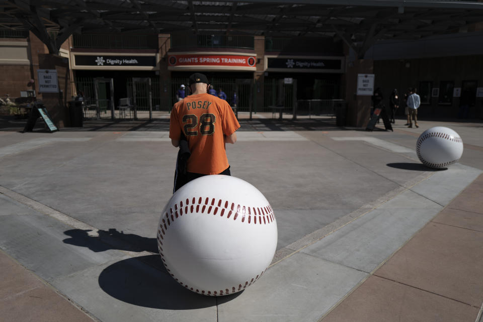 Dan Munson, 37, of Atlanta, waits for the gates to open at Scottsdale Stadium before a spring baseball game between the San Francisco Giants and the Los Angeles Angels in Scottsdale, Ariz., Sunday, Feb. 28, 2021. (AP Photo/Jae C. Hong)