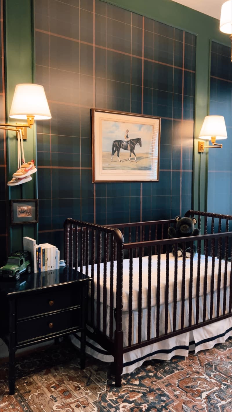 Green tartan wall covering flanked by sconces  behind crib in baby nursery