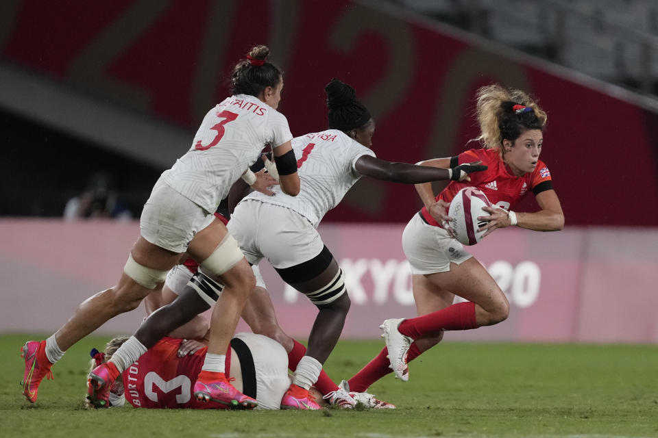 Britain's Abbie Brown, right, takes off with the ball, pursued by Cheta Emba and Abby Gustaitis of the United States, in their women's rugby sevens quarterfinal match at the 2020 Summer Olympics, Friday, July 30, 2021 in Tokyo, Japan. (AP Photo/Shuji Kajiyama)