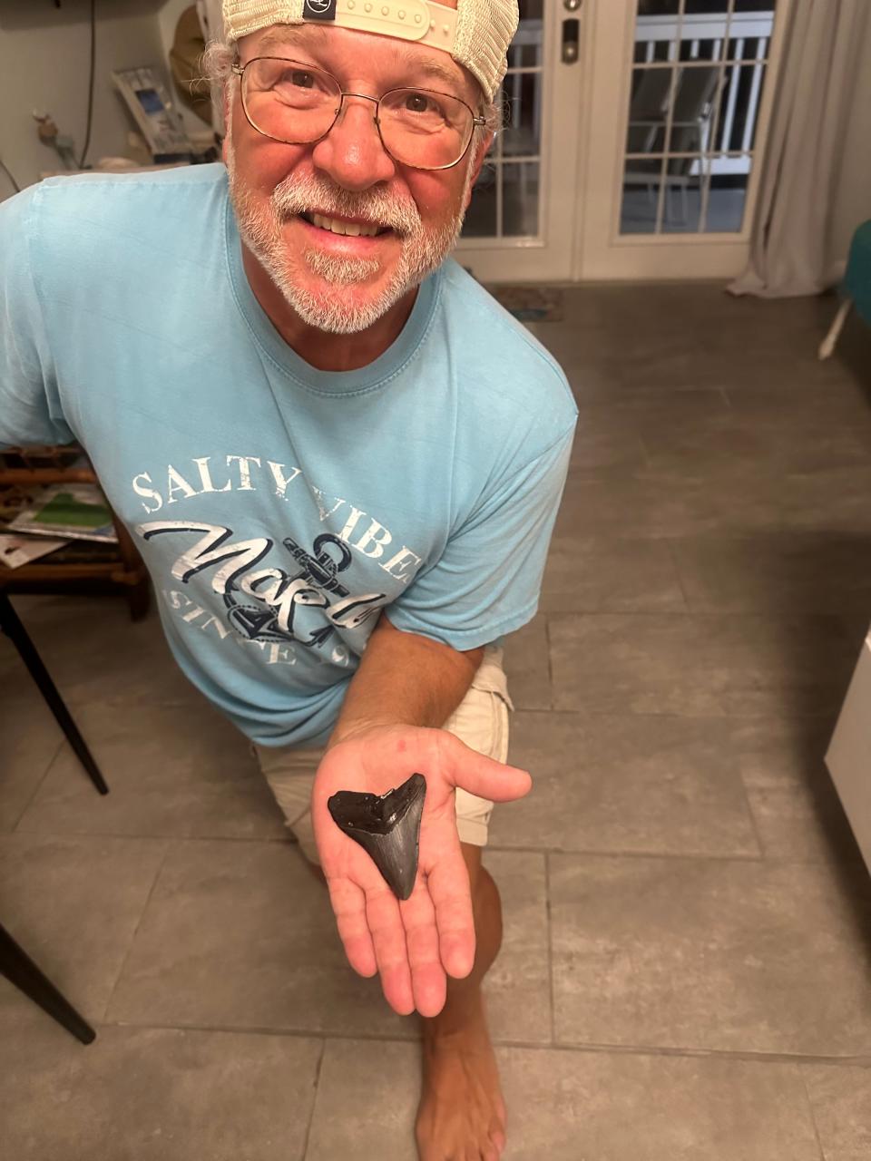 Brad Vanderstow holds the large Megalodon tooth he found on South Englewood beach near Stump Pass on March 6.