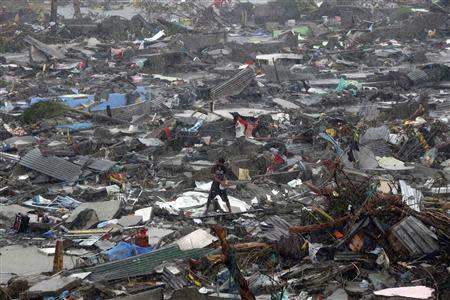 A man stands atop debris as residents salvage belongings from the ruins of their houses after Typhoon Haiyan battered Tacloban city in central Philippines