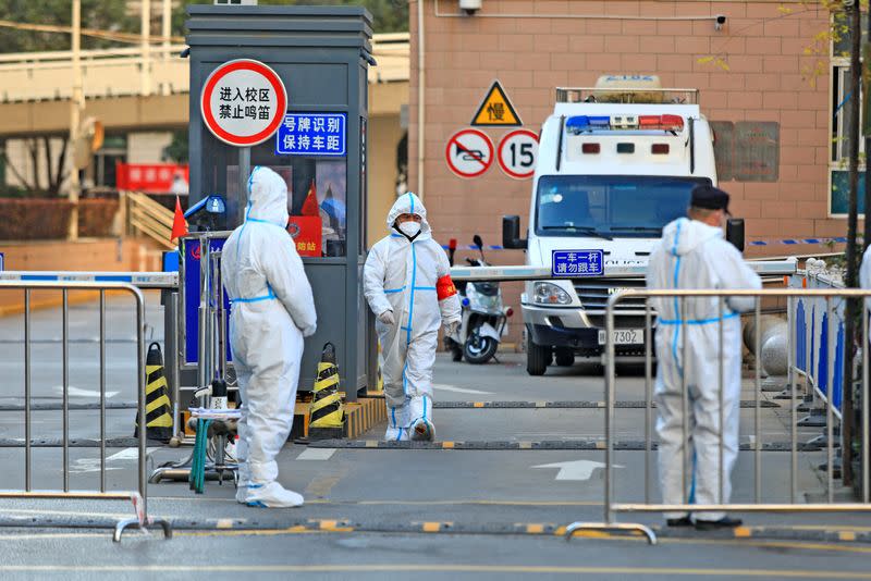 FILE PHOTO: Workers stand at a residential area under lockdown following COVID-19 outbreak in Xian