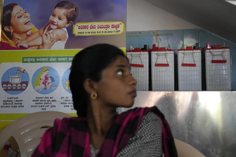 A pregnant woman who had come for her routine checkup looks at the batteries used with rooftop solar to provide electricity to Zaheerabad health care center, in Raichur, India, Wednesday, April 19, 2023. In semi-urban and rural regions of India and other developing countries with unreliable power grids, decentralized renewable energy — especially solar — is making all the difference in delivering modern health care. (AP Photo/Aijaz Rahi)