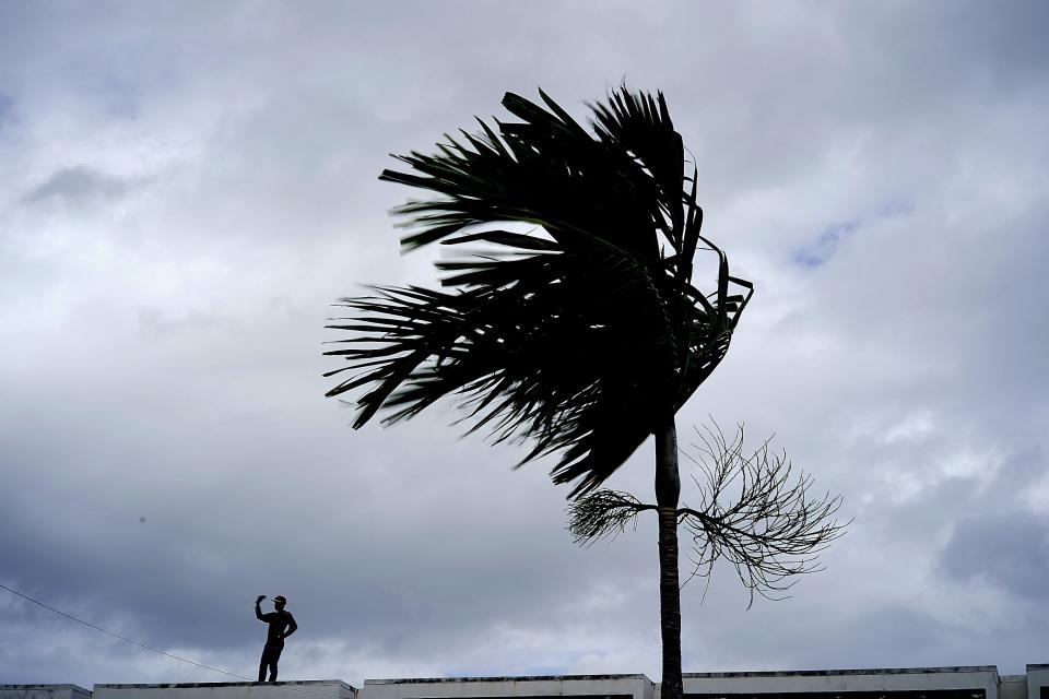 A man stands on a store's roof as he works to prepare it for the arrival of Hurricane Dorian in Freeport on Grand Bahama, Bahamas, Sunday, Sept. 1, 2019. Hurricane Dorian intensified yet again Sunday as it closed in on the northern Bahamas, threatening to batter islands with Category 5-strength winds, pounding waves and torrential rain. (AP Photo/Ramon Espinosa)