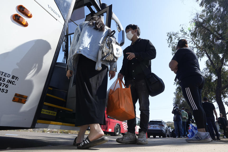 A couple from China board a bus to the airport after crossing the border and being dropped off by Border Patrol agents at a transit center Wednesday, Oct. 18, 2023, in San Diego. A major influx of Chinese migration to the United States on a relatively new and perilous route through Panama's Darién Gap jungle has become increasingly popular thanks to social media. (AP Photo/Gregory Bull)