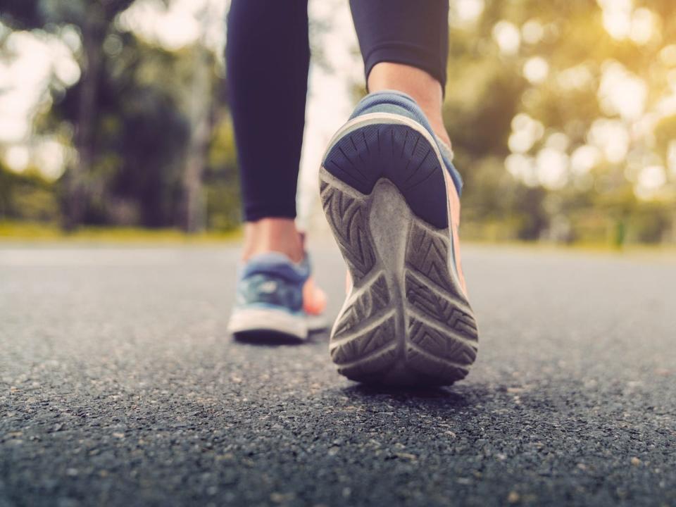 Frauen Füße in Sportschuhen gehen über Asphalt