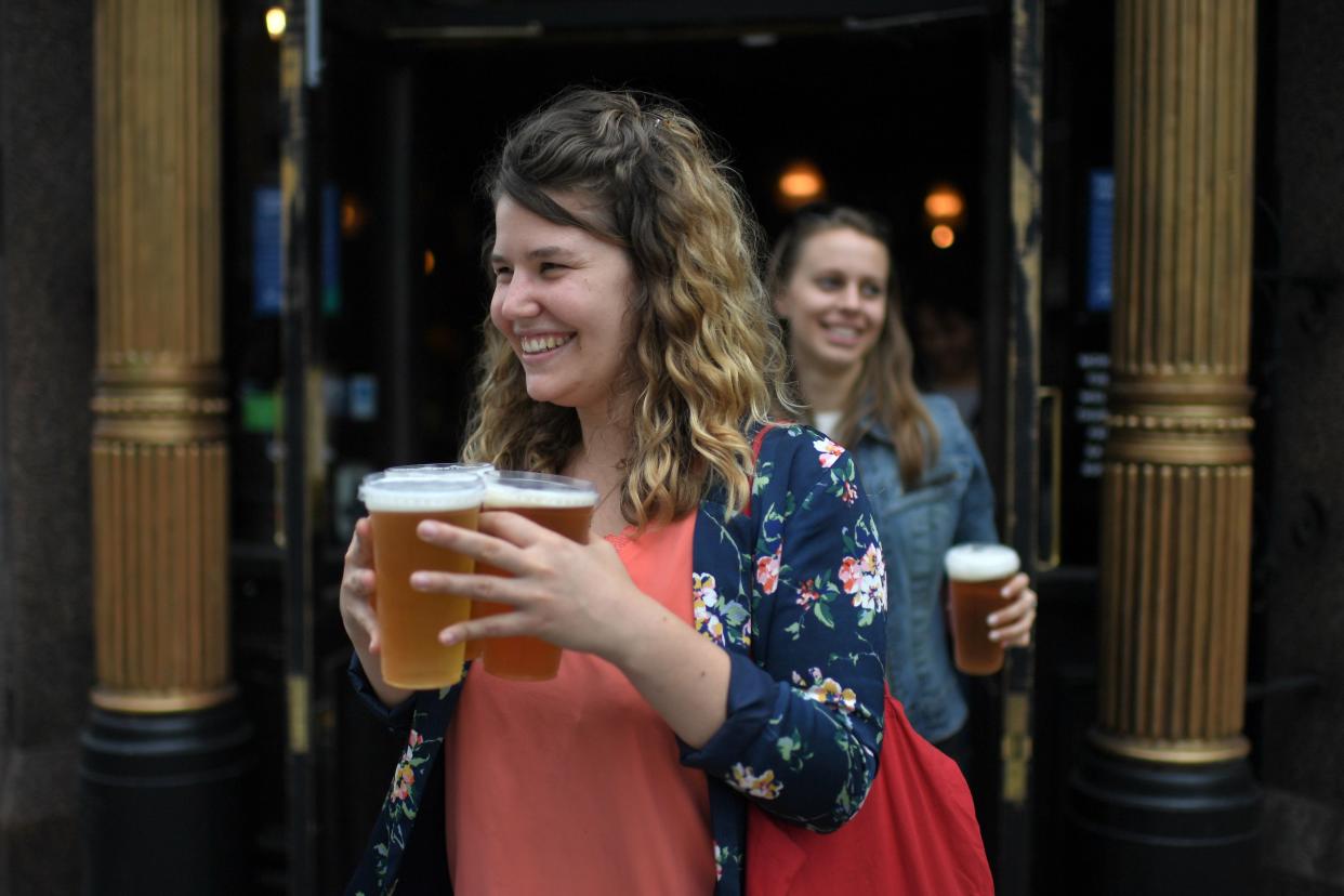 Customers leave with pints of beer for takeaway at The Ten Bells pub in east London on June 27, 2020. - The pub serves drinks for takeaway to maintain social distancing and coronavirus lockdown regulations. Prime Minister Boris Johnson wants pubs and restaurants to be buzzing in the curtailed summer season, despite continued social distancing rules and restrictions. (Photo by DANIEL LEAL-OLIVAS / AFP) (Photo by DANIEL LEAL-OLIVAS/AFP via Getty Images)