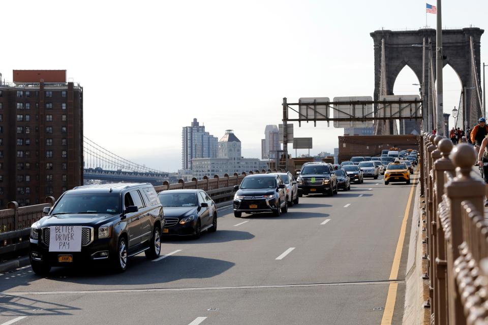 Uber and Lyft drivers, with signs on their vehicles supporting better wages, cross the Brooklyn Bridge in May in a caravan of about 25 vehicles as they protested against Uber's then-imminent IPO.