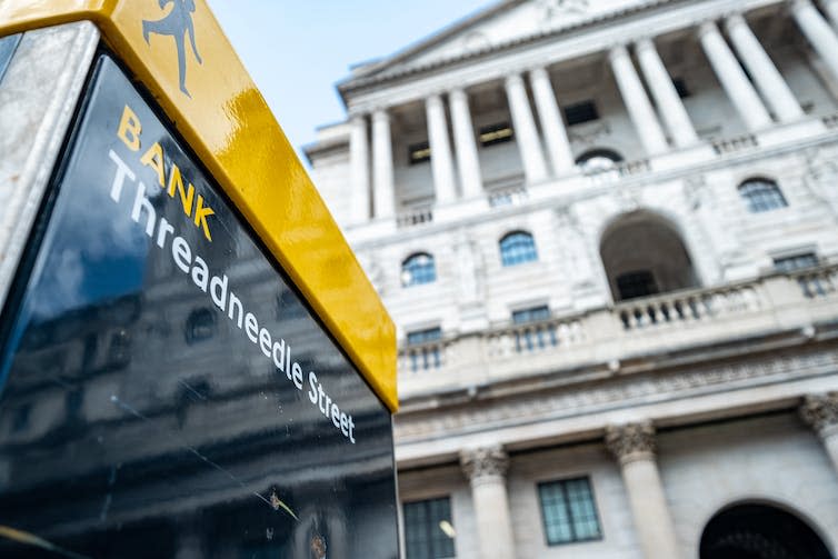 Sign for Bank station and Threadneedle Street in front of the Bank of England building.