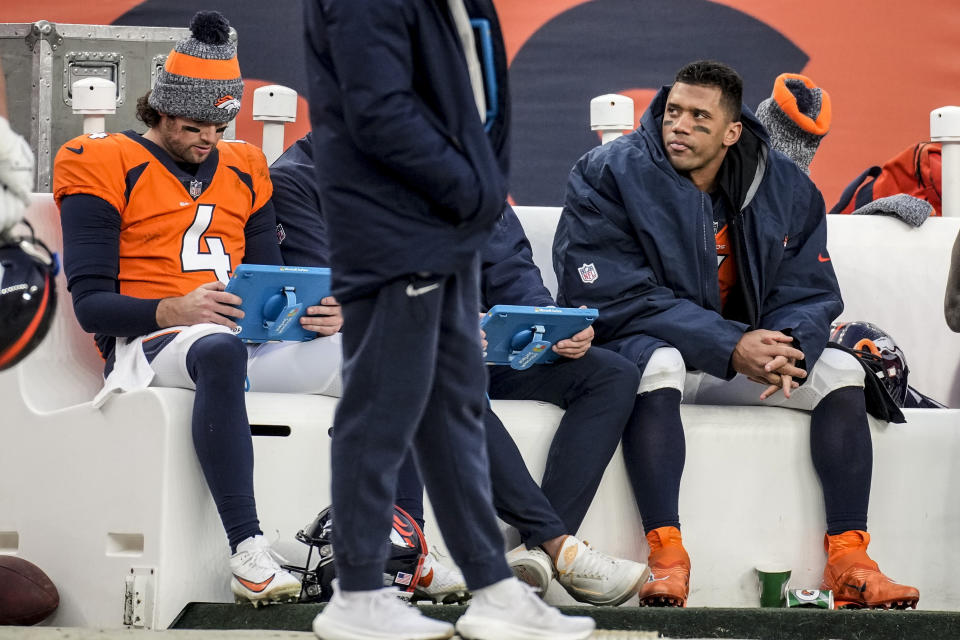 Denver Broncos quarterback Russell Wilson, right sits on the bench with Denver Broncos quarterback Jarrett Stidham (4) during the second half of an NFL football game against the Los Angeles Chargers, Sunday, Dec. 31, 2023, in Denver. (AP Photo/David Zalubowski)