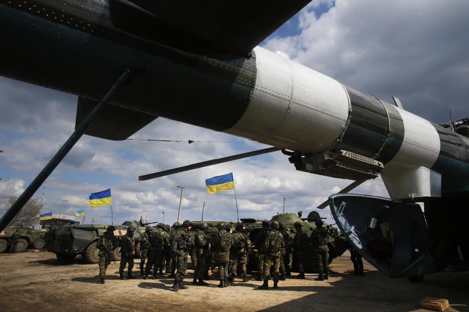 Ukrainian Army troops receive munitions at a field on the outskirts of Izyum, Eastern Ukraine, Tuesday, April 15, 2014. An Associated Press reporter saw at least 14 armored personnel carriers with Ukrainian flags, one helicopter and military trucks parked 40 kilometers (24 miles) north of the city on Tuesday. (AP Photo/Sergei Grits)