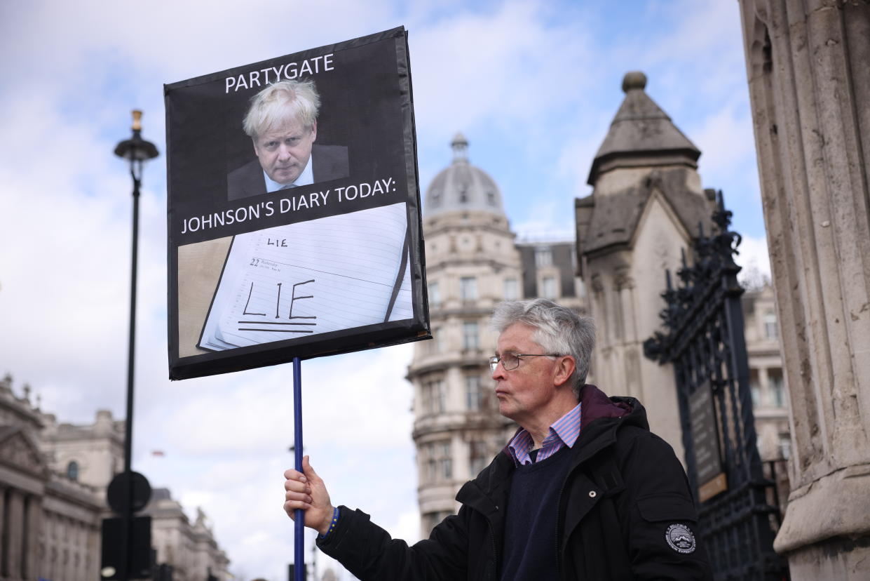 LONDON, ENGLAND - MARCH 22:  A protester holds a sign outside parliament as Boris Johnson gives evidence to Partygate Committee on March 22, 2023 in London, England. The former prime minister attends a televised evidence session in front of the Commons Privileges Committee, which has previously suggested that Johnson misled Parliament in his statements about parties at Number 10 during the Covid-19 lockdown. (Photo by Dan Kitwood/Getty Images)