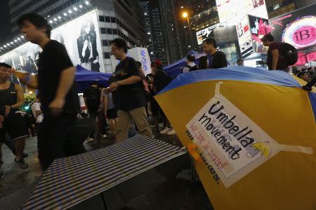 Protesters walk past an umbrella as they block the main road at Causeway Bay shopping district in Hong Kong September 30, 2014. REUTERS/Bobby Yip
