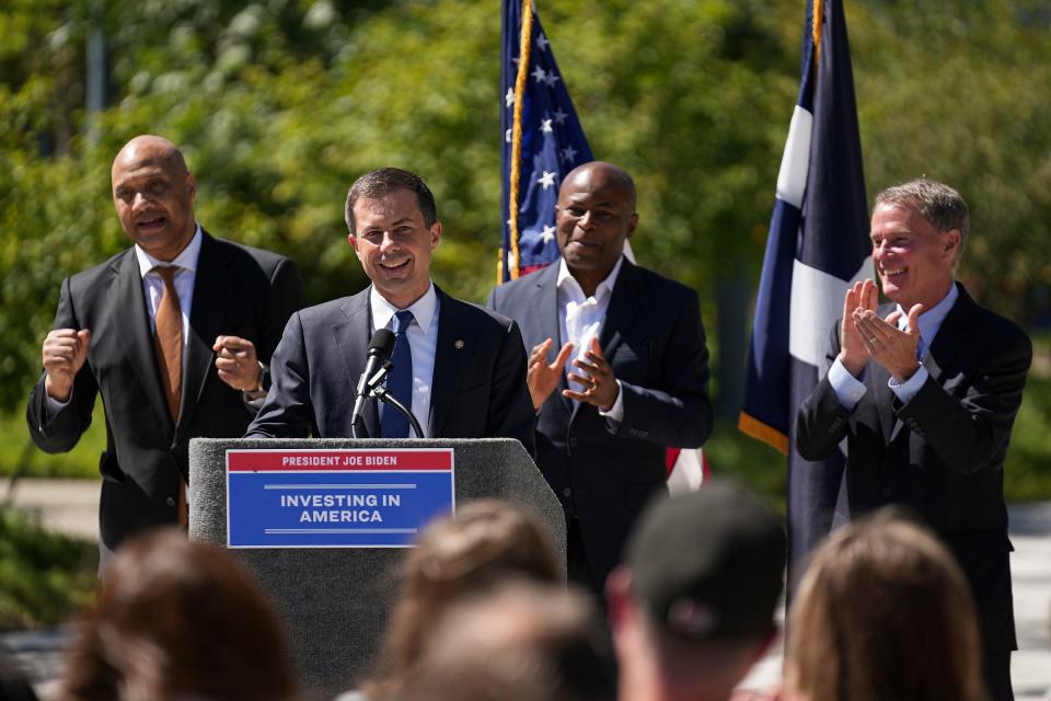 United States Secretary of Transportation Pete Buttigieg speaks at a podium Thursday, Aug. 31, 2023, as Congressman André Carson (from left), City Council President Vop Osili and Mayor Joe Hogsett clap, outside Cummins Indianapolis Distribution Headquarters in downtown Indy. Buttigieg made several stops in Indiana to highlight infrastructure investments the Biden administration has made. During his speech, Buttigieg commended a $46.5 million city project that is partially federally funded by the Bipartisan Infrastructure Law. The project, which is at least two years away from beginning, will reconfigure and improve to downtown roads for safety and efficiency.