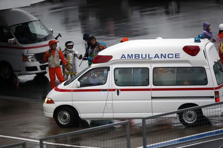 Marshalls clear the way for an ambulance after the race was stopped following a crash by Marussia Formula One driver Jules Bianchi of France at the Japanese F1 Grand Prix at the Suzuka Circuit October 5, 2014. REUTERS/Yuya Shino