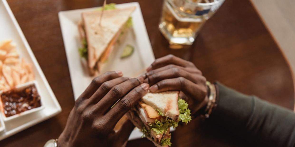 cropped image of african american man holding sandwich