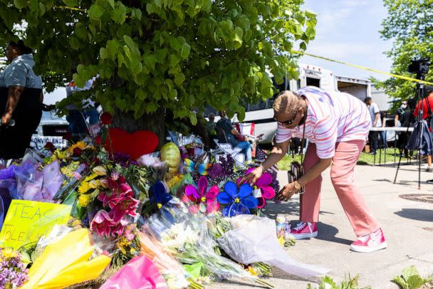 PHOTO: Cecilia Lawson lays flowers at a memorial set up across the street from a Tops Friendly Market grocery store where a gunman killed ten people and wounded three others i Buffalo, New York, May 15, 2022.  (The Washington Post via Getty Images, FILE)