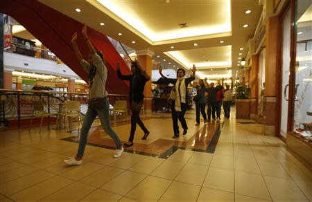 Shoppers and shop assistants raise their hands as they are escorted to safety while armed police hunt gunmen who went on a shooting spree in Westgate shopping centre in Nairobi September 21, 2013. REUTERS/Goran Tomasevic