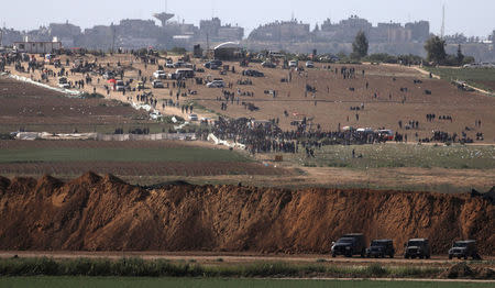 Israeli military vehicles are seen next to the border on the Israeli side of the Israel-Gaza border, as Palestinians demonstrate on the Gaza side of the border, March 31, 2018. REUTERS/Ammar Awad