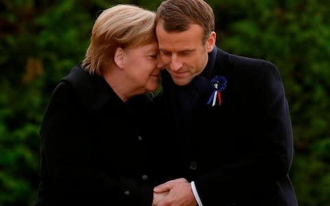Emmanuel Macron and Angela Merkel hug after unveiling a plaque as part of the Armistice commemorations - Credit: AFP