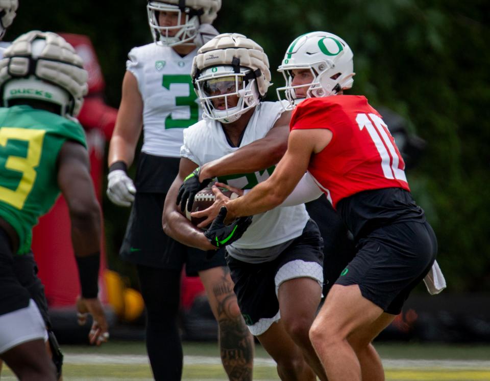 Oregon quarterback Bo Nix, right, hands off the ball to running back Byron Cardwell during practice on Wednesday in Eugene.