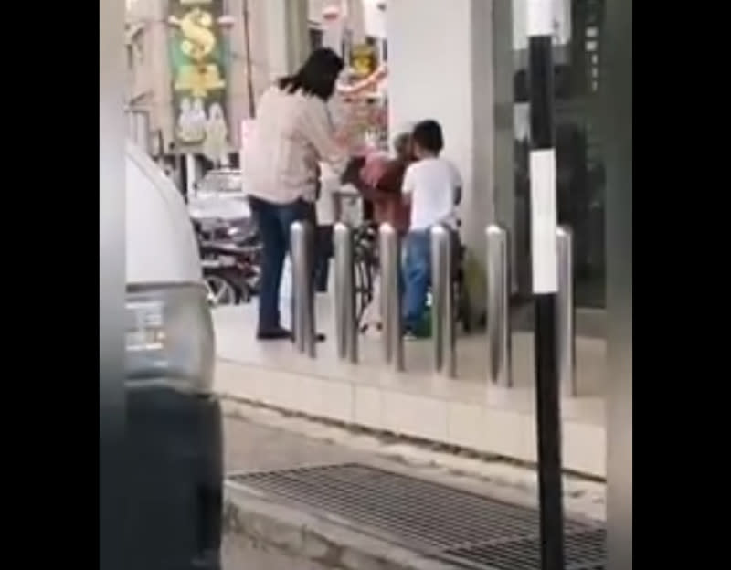 Little Fatih hands the hungry man a packet of food outside a Maybank in Nibong Tebal. — Screengrab from Facebook/Penang Kini