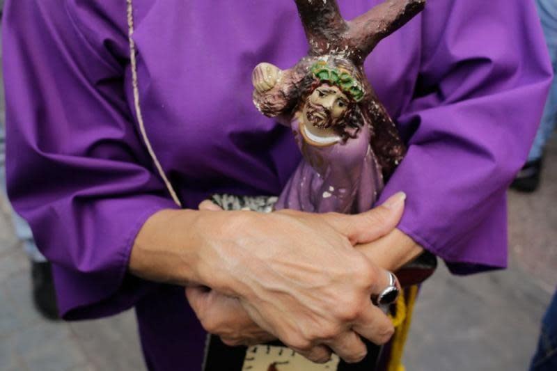 Manos de un nazareno cruzadas sobre un cristo