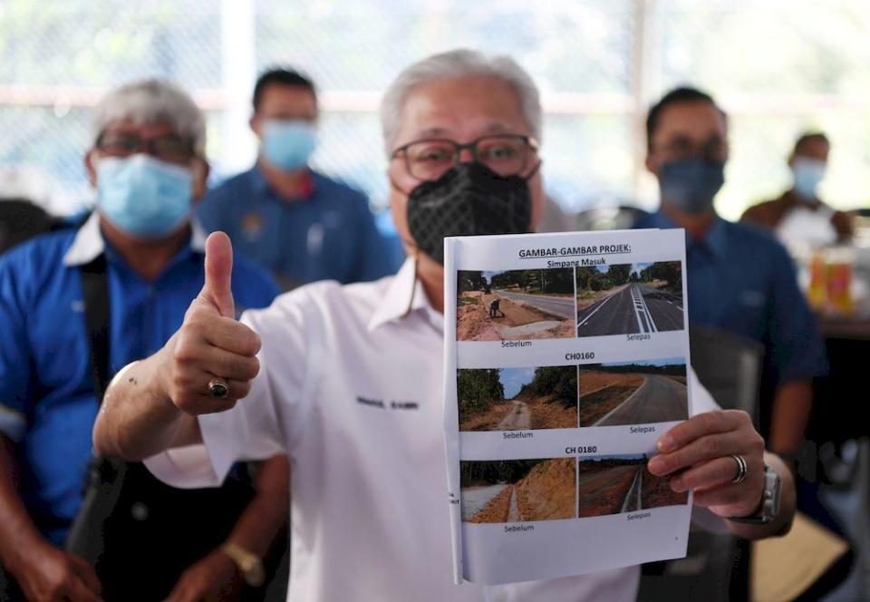 Senior Minister Datuk Seri Ismail Sabri Yaakob, who is also Bera Member of Parliament, showing before-and-after pictures of the road construction from Kampung Chuat to Kampung Bukit Imam Sulong, in Bera, April 11, 2021. — Bernama pic