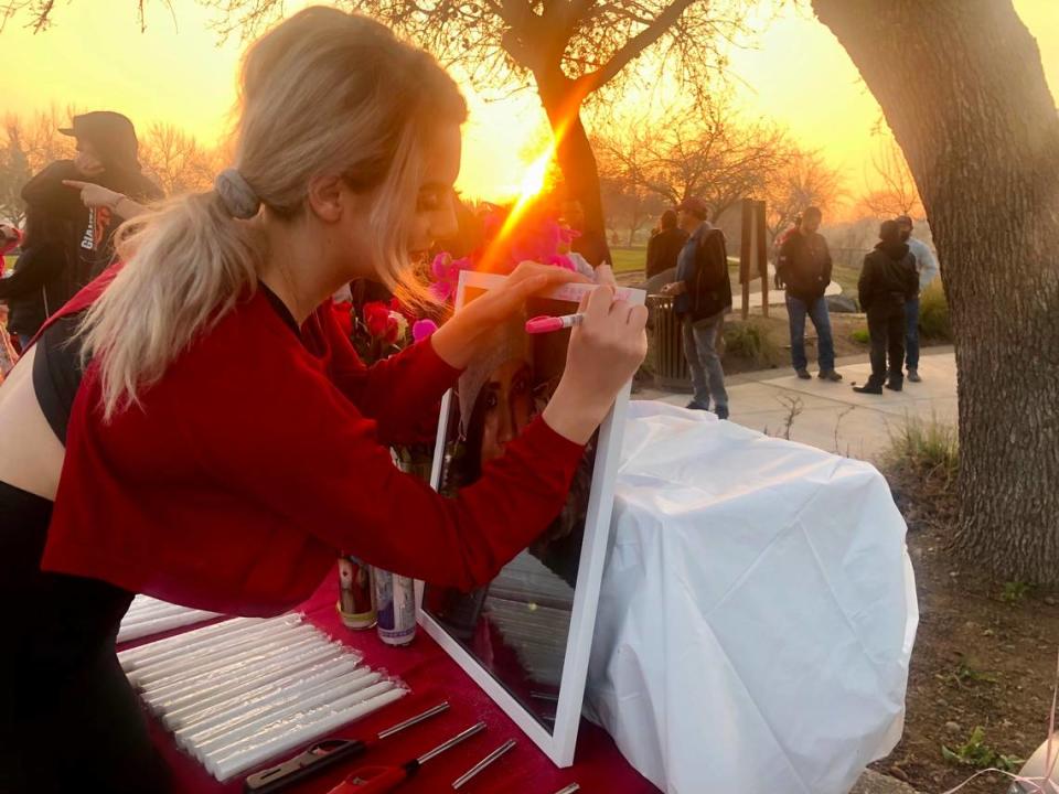 Camille Prather, 21, of Oakdale, writes a note on a framed photo of her friend, Rebekah Gall, 27, who died in a car crash after an alleged drunk driver hit her. 