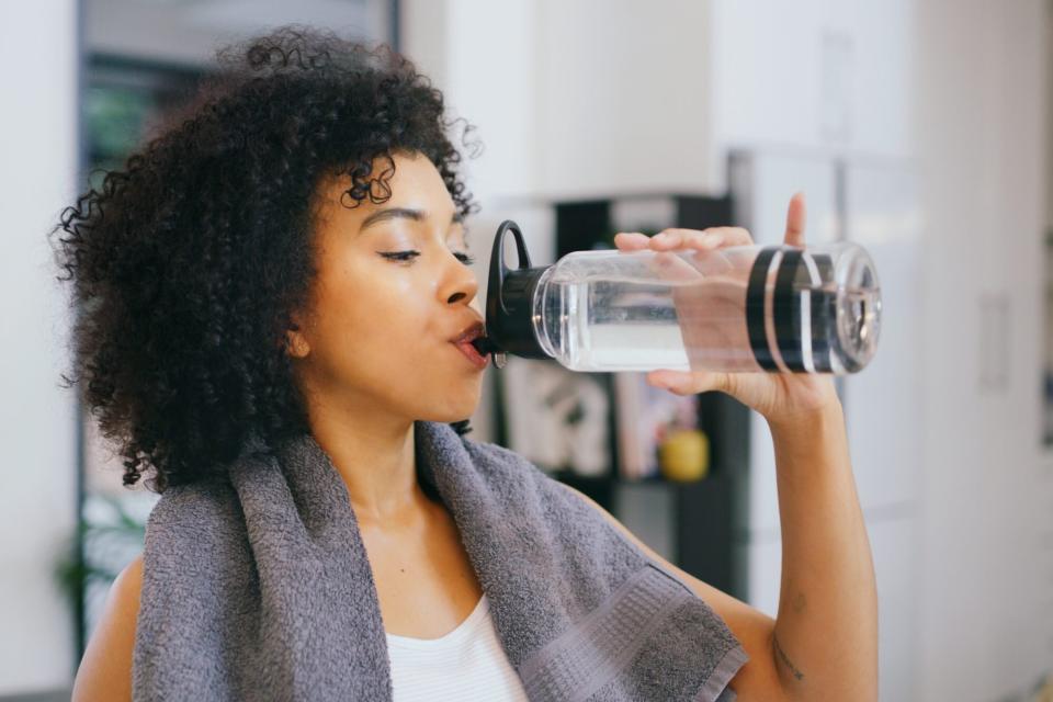 woman drinking water from water bottle while working out
