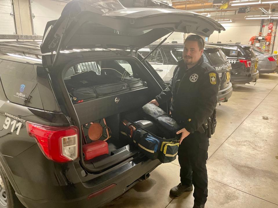 Officer Michael Klawitter explains the contents of a squad car's trunk. Officers travel with an empty gas can, emergency cones and other equipment stashed in bags and drawers.