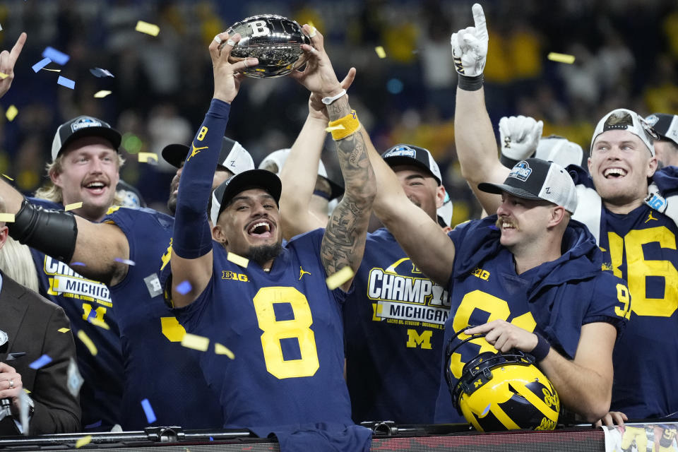 Michigan wide receiver Ronnie Bell holds the trophy as he celebrates with teammates after defeating Purdue in the Big Ten championship NCAA college football game, early Sunday, Dec. 4, 2022, in Indianapolis. Michigan won, 43-22. (AP Photo/AJ Mast)