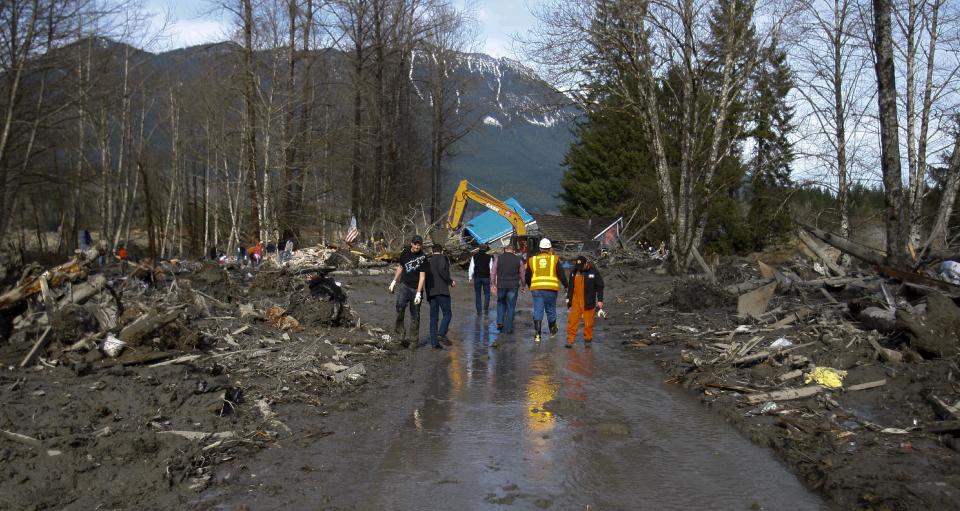 In Oso, Wash., Monday, March 24, 2014,Washington Gov. Jay Inslee and a small entourage walk eastward on a cleared swath of SR 530, toward the first house that lies in a heap across the highway. (AP Photo /The Herald, Dan Bates)